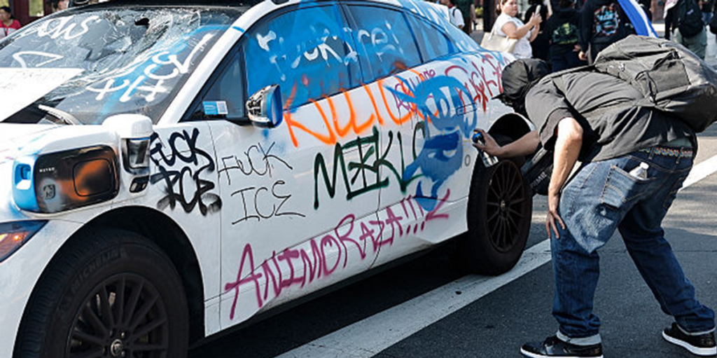Protesters against ICE vandalize a group of self-driving cars