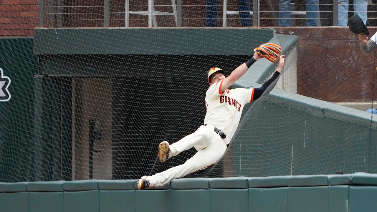 Yastrzemski of the Giants jumps over the wall to make an impressive catch