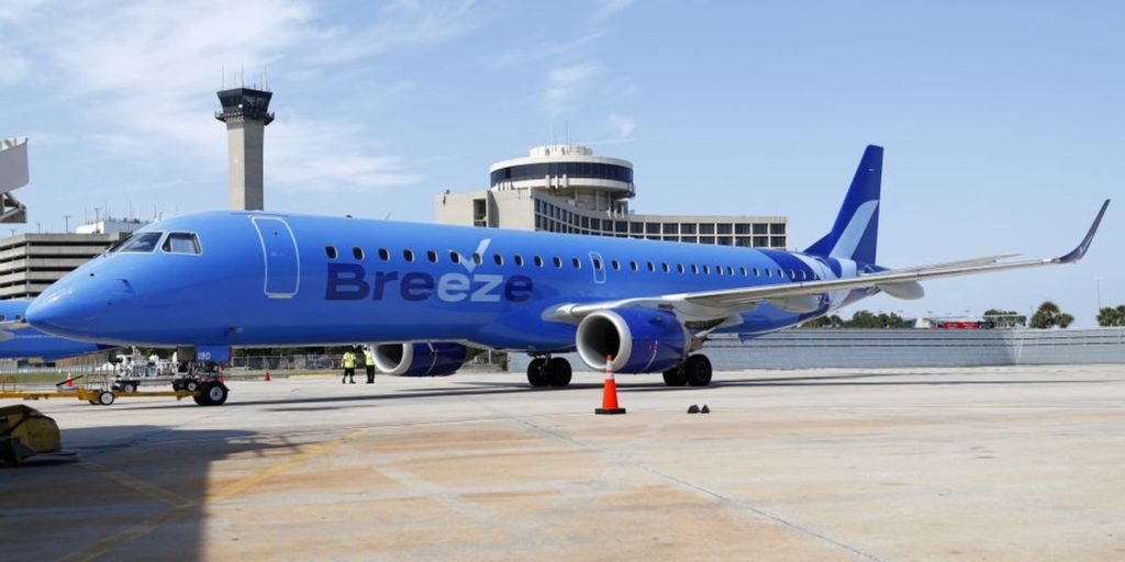 Footage captures large passenger restraining intoxicated, disruptive individual David Leroy Carter, who shouted racist remarks and led to emergency landing of Breeze Airways flight.