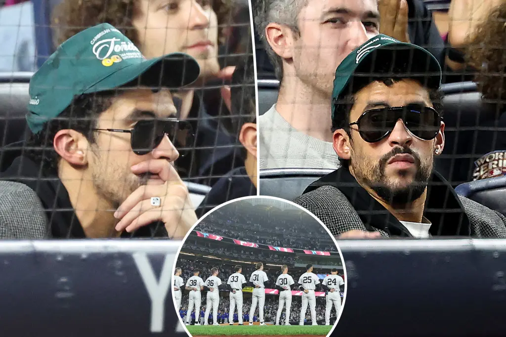 Bad Bunny is seated during God Bless America at Yankee Stadium during the MLB playoff game.