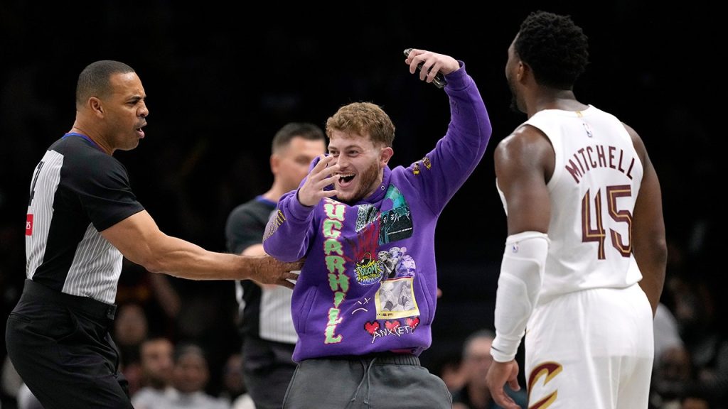 Fan rushes onto the court for a selfie with Donovan Mitchell during Nets game