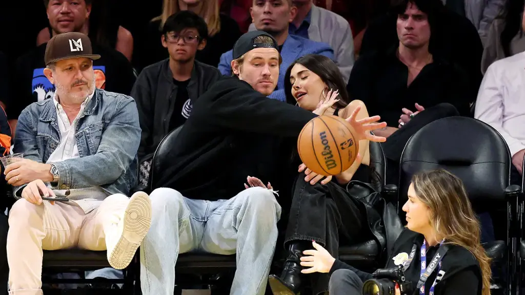 Justin Herbert shields Madison Beer from a basketball at a Lakers game