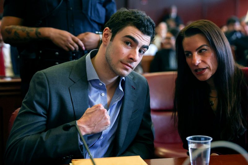 Mangione confidently raises his fist as his defense team questions the validity of evidence from his arrest.