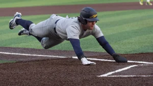 Players rush onto the field during college baseball game following tough play.