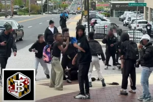 Group of middle schoolers laugh and smile for the camera while classmates attack a victim in a chaotic street fight