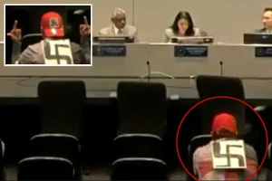Individual wearing a swastika makes inappropriate gestures at police officials.