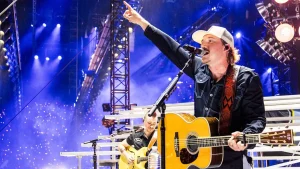 Fan of Morgan Wallen gains attention for kicking a phone from someone's hand while being taken away in handcuffs.