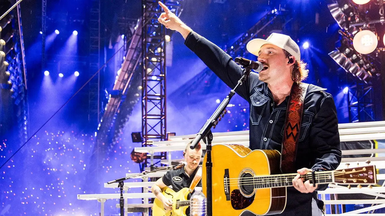 Fan of Morgan Wallen gains attention for kicking a phone from someone's hand while being taken away in handcuffs.