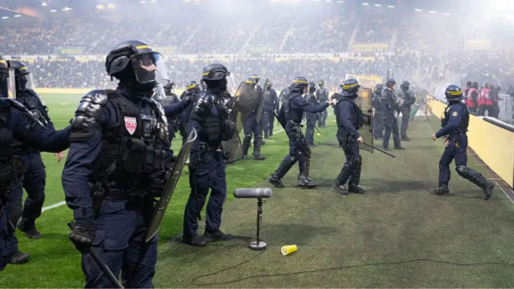 Nantes fans clash with security and invade the field during a chaotic football match.