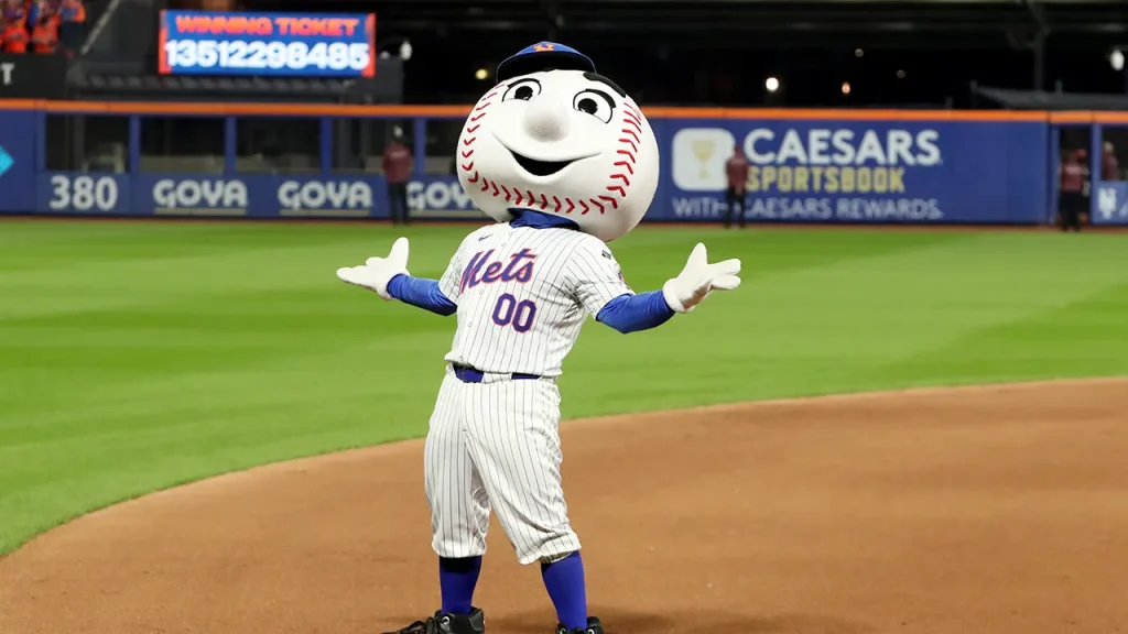 Mets reporter analyzes the team's tough season as Mr. Met dances during Pride Night in the background
