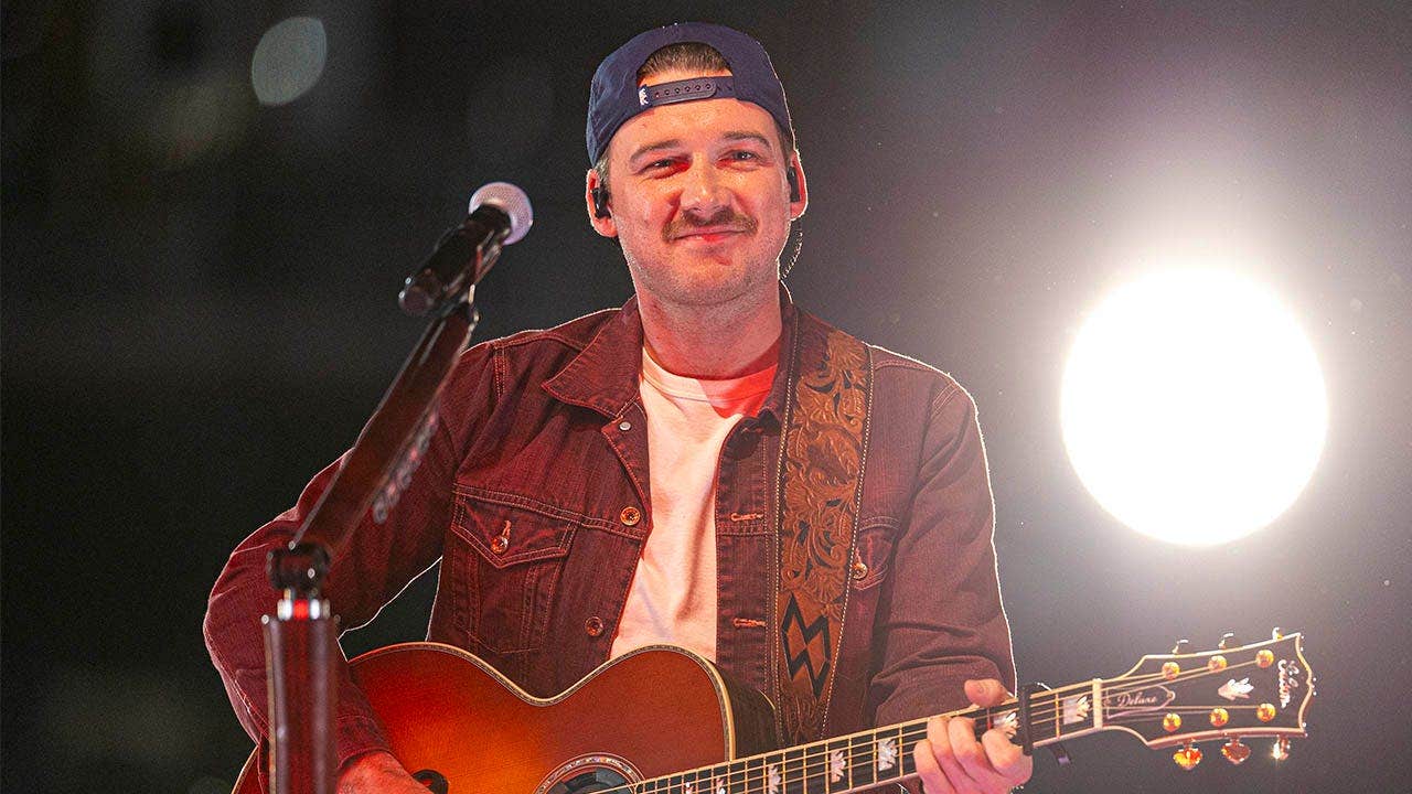 Morgan Wallen showcases his Christian faith by displaying a Bible verse on his arm during a performance.