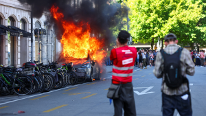 Protesters burn a Tesla and break windows at a UN office during an anti-G7 demonstration.