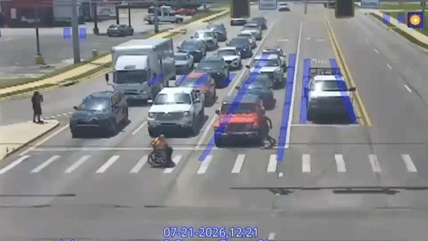 Person in Spider-Man outfit assists man in wheelchair crossing the street in Arkansas