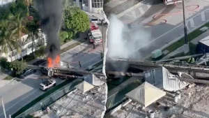 A construction rig falls onto three cars in Miami, leaving two workers trapped.