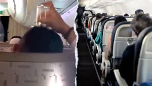 A passenger on an EVA Air flight uses a drinking glass to scratch his head during the flight.